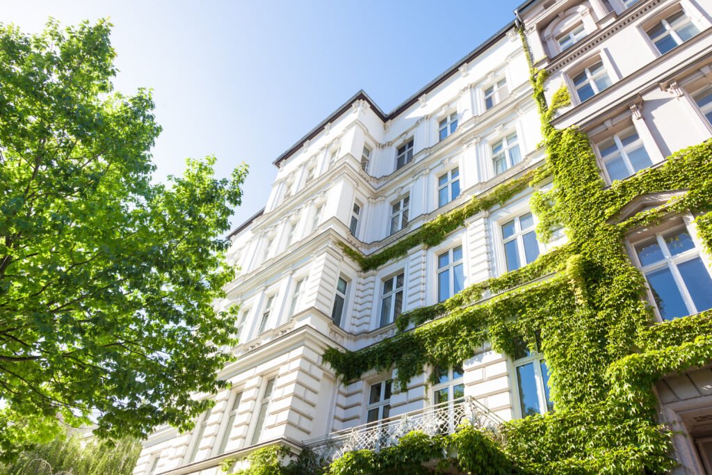 Altbau und Bäume in Deutschland Mehrgeschossiges Mietshaus grün behangen an der Fassade
